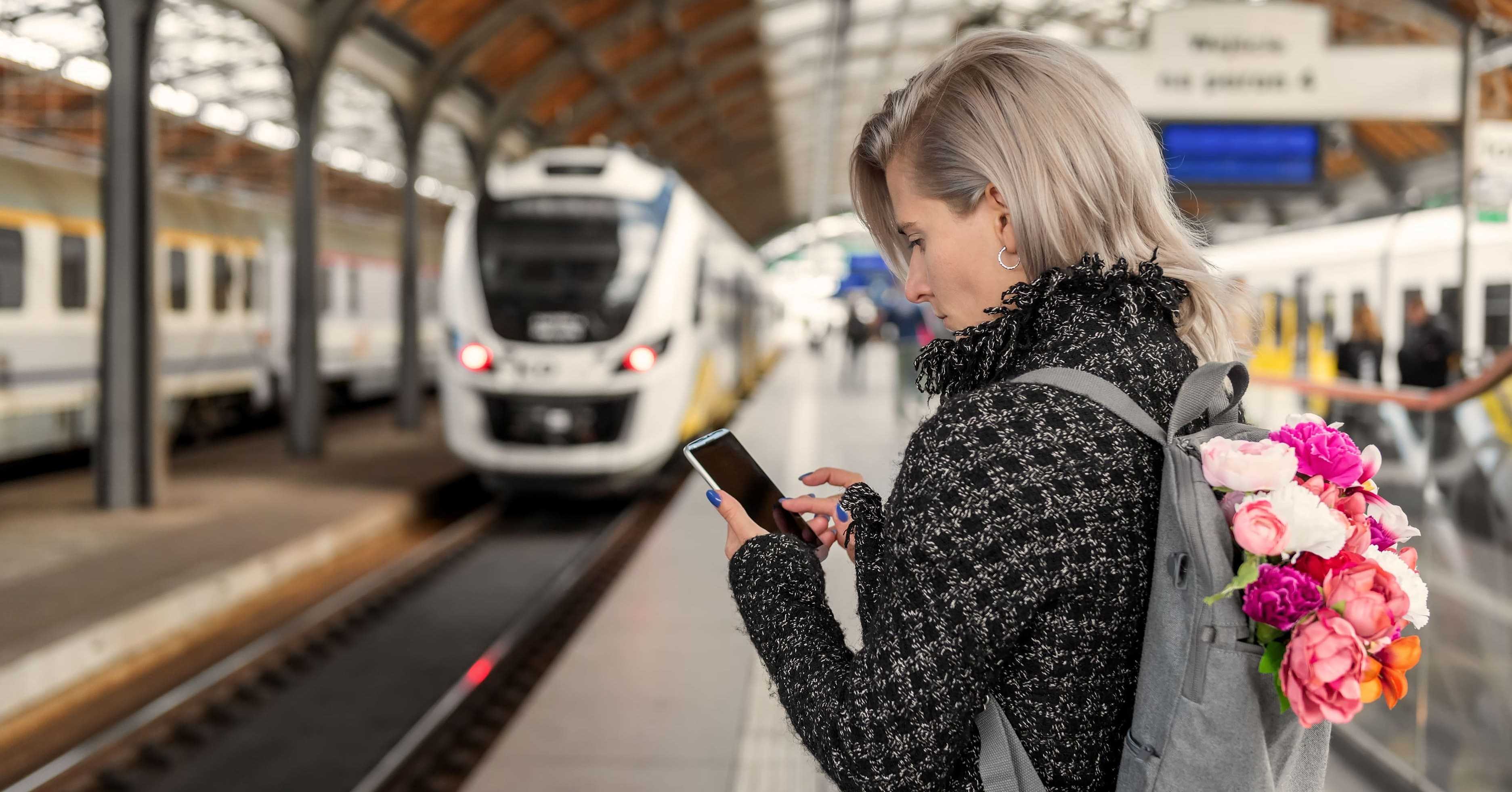 woman using WiFi on phone at train station