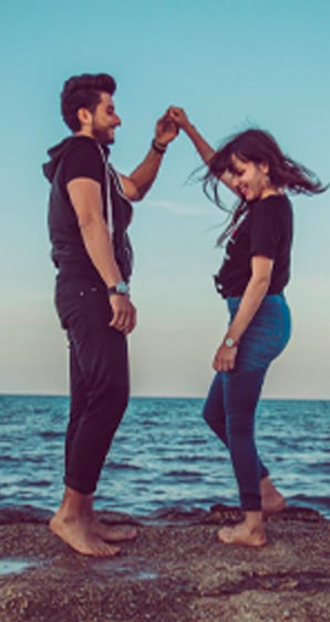man and woman standing rock by the shore
