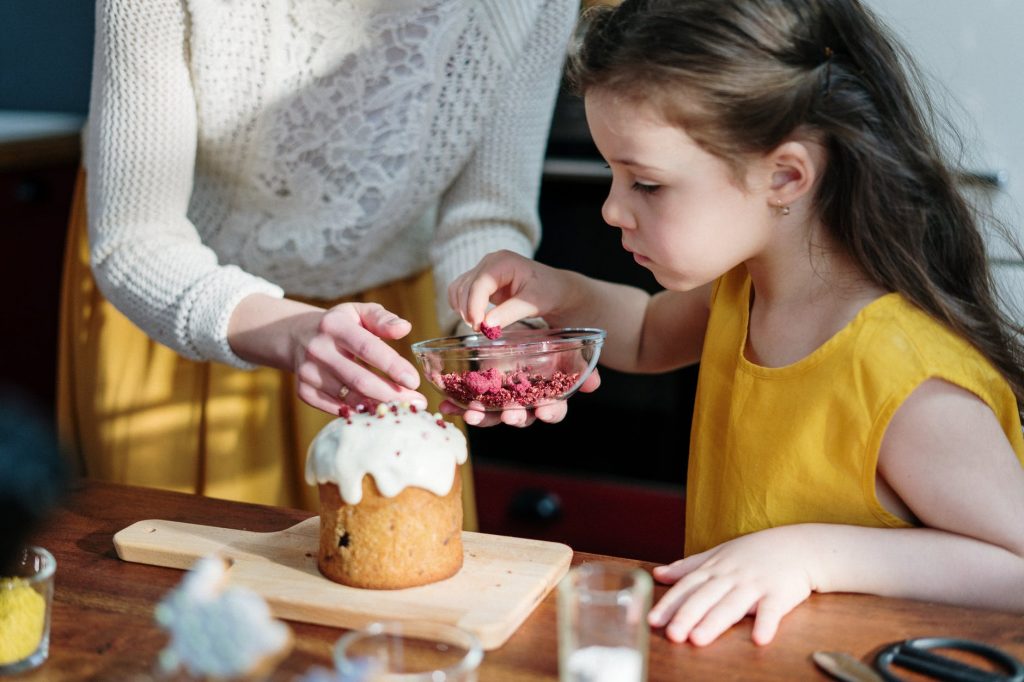 Criança decorando um bolo junto com sua mãe como exemplo de culinária infantil