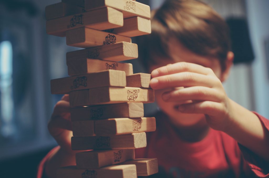 Aprendizagem criativa no ensino infantil 3 Criança brincando com blocos de madeira representando aprendizagem criativa.