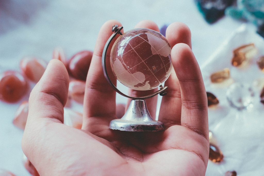 Foco em uma mão segurando um globo em miniatura, representando a língua inglesa no mundo.