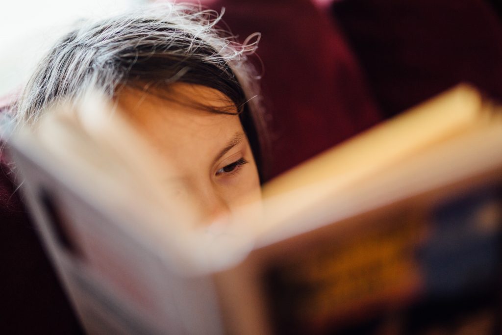 Criança em desenvolvimento de linguagem lendo um livro.
