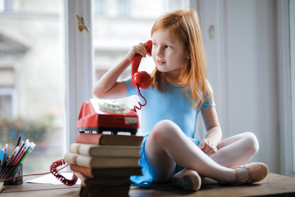 Criança falando ao telefone e treinando para teste de proficiência em inglês