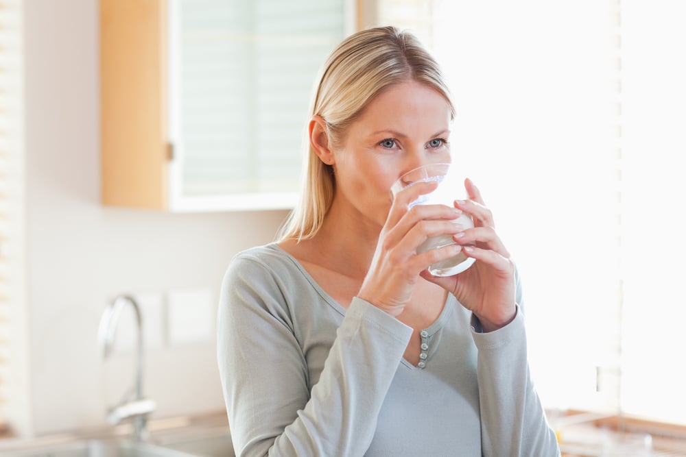 Young woman in the kitchen drinking water