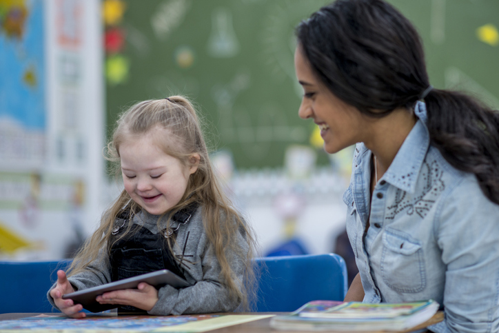 teacher showing girl with autism how to use audio device