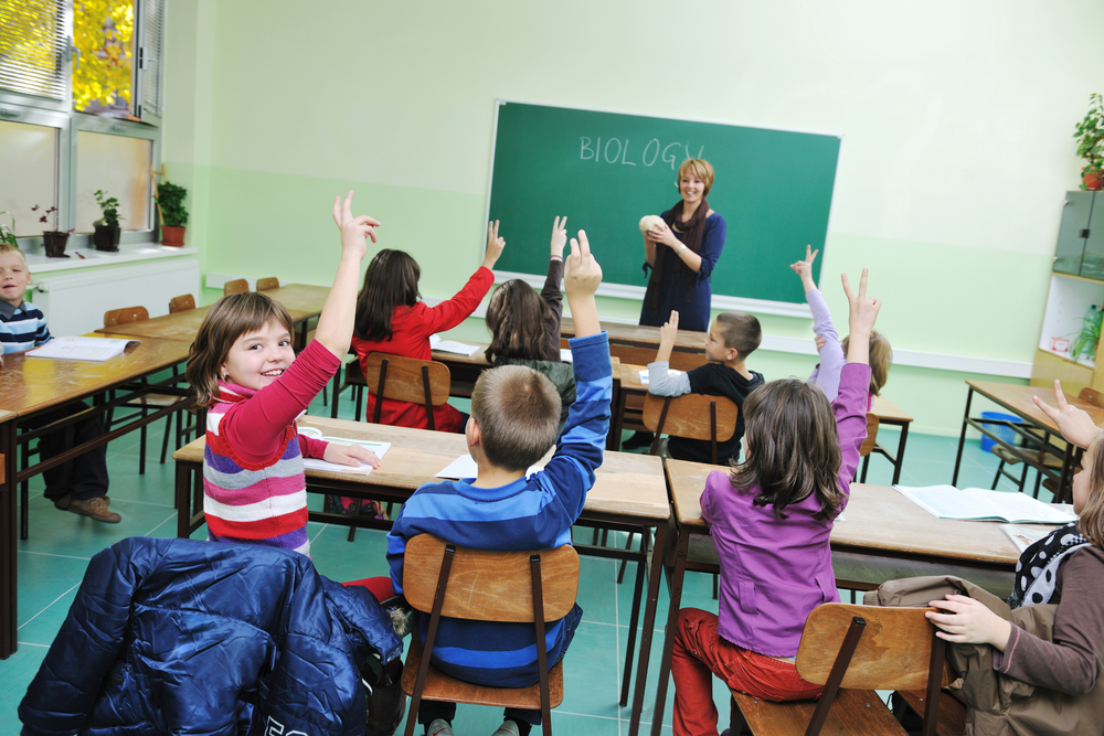 happy children group in school classrom taking notes and learning biology and anatomy lessons with teacher-1