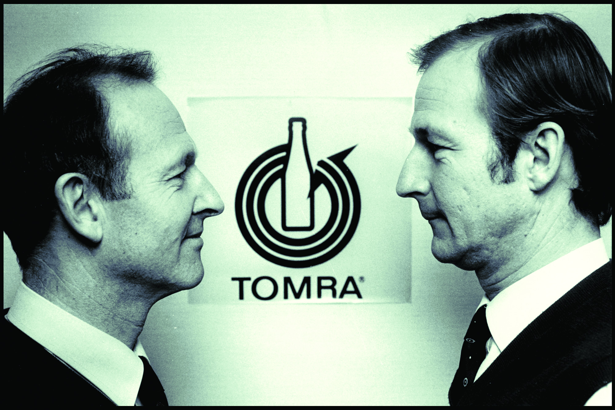 TOMRA founders Petter and Tore Planke standing in front of original TOMRA logo-1