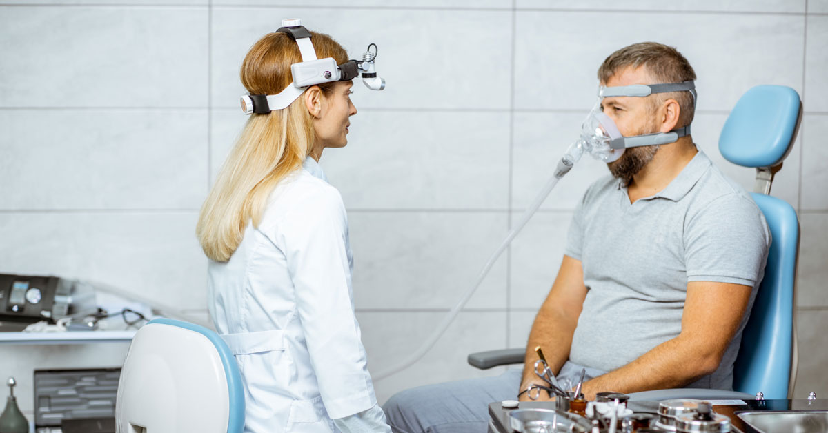 Man wearing a sleep apnea mask with a clinician